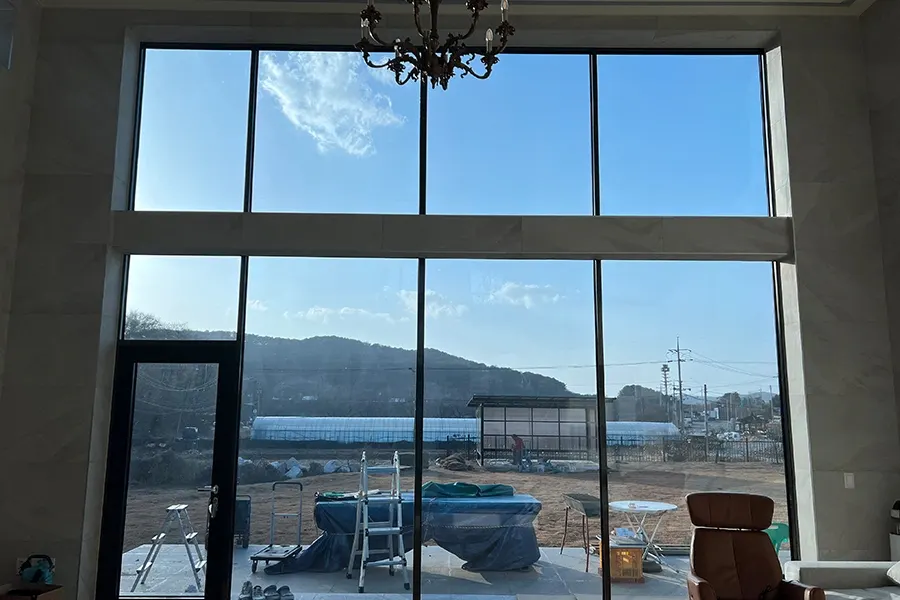 시공 전 거실 내부에서 바라본 통창, 산과 하늘이 맑게 비치는 모습