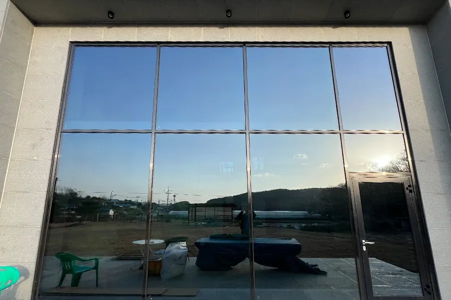 시공이 끝난 통창 외관, 노을빛이 유리에 반사되는 저녁 풍경